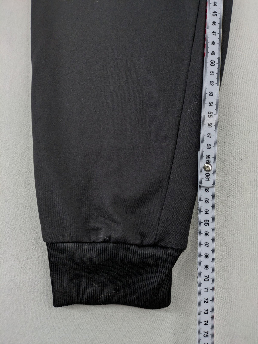 Kalenji black loungewear pants with grey accents and zippered side pockets.