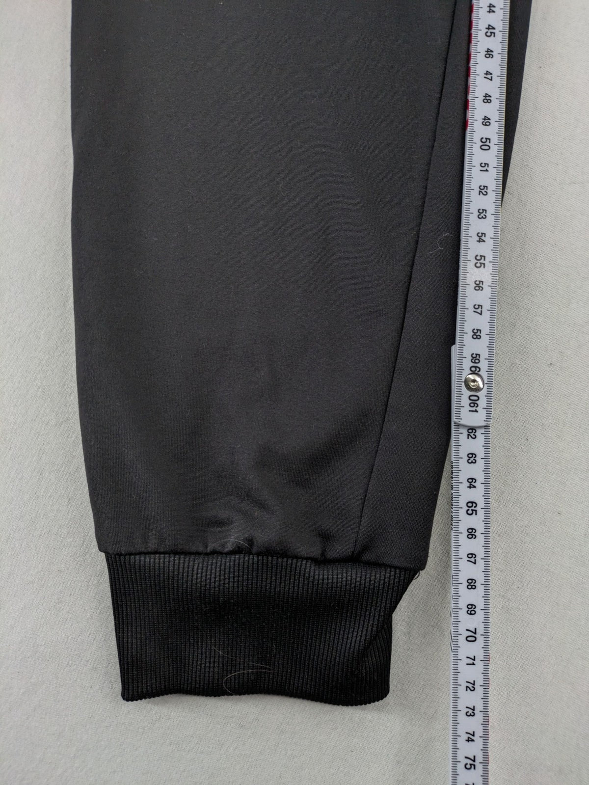 Kalenji black loungewear pants with grey accents and zippered side pockets.