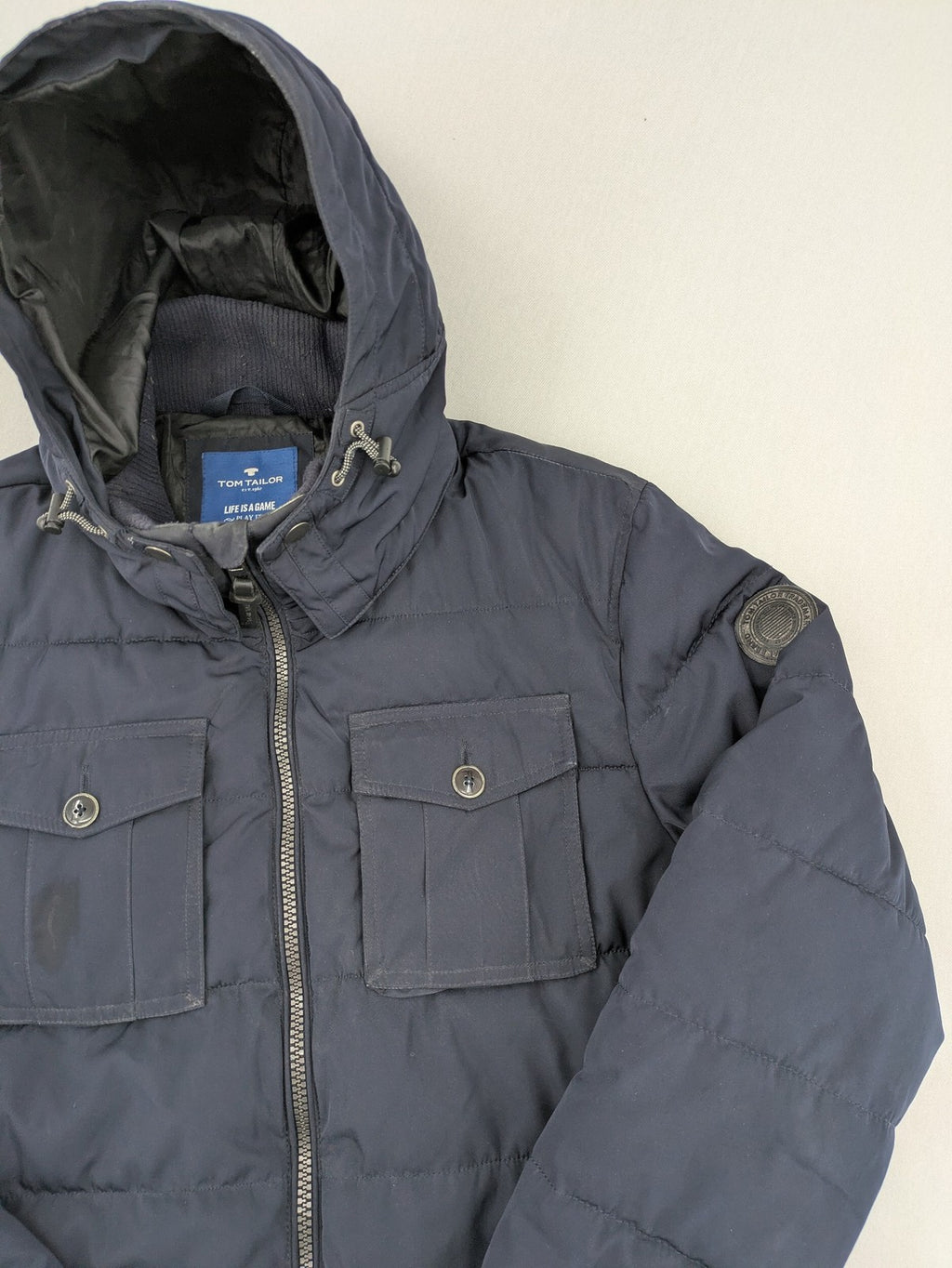 Tom Tailor navy puffer jacket with quilted design and adjustable hood, featuring multiple pockets.