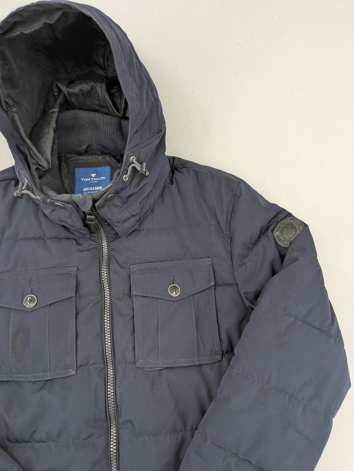 Tom Tailor navy puffer jacket with quilted design and adjustable hood, featuring multiple pockets.