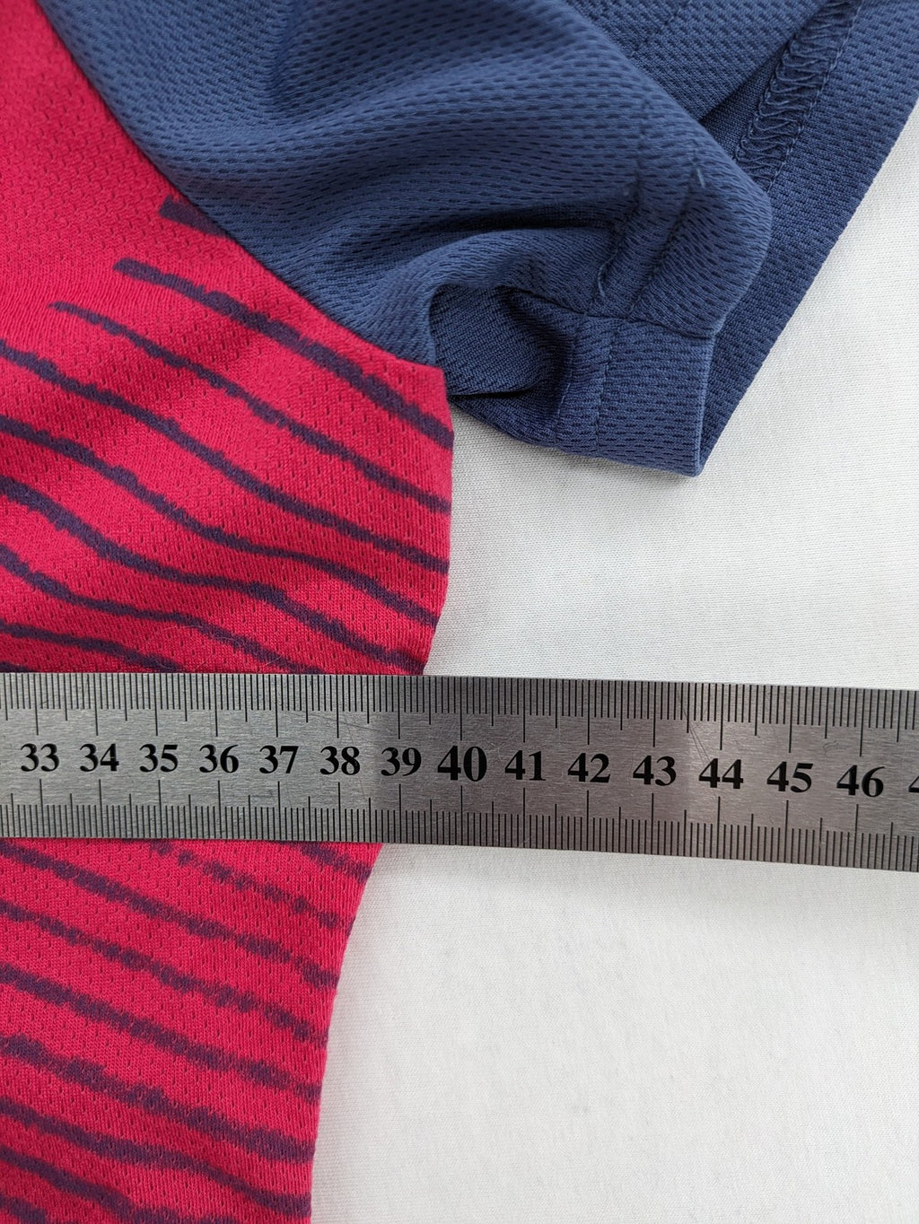 Muster blue and red short-sleeve functional shirt with dynamic wave pattern and raglan sleeves.