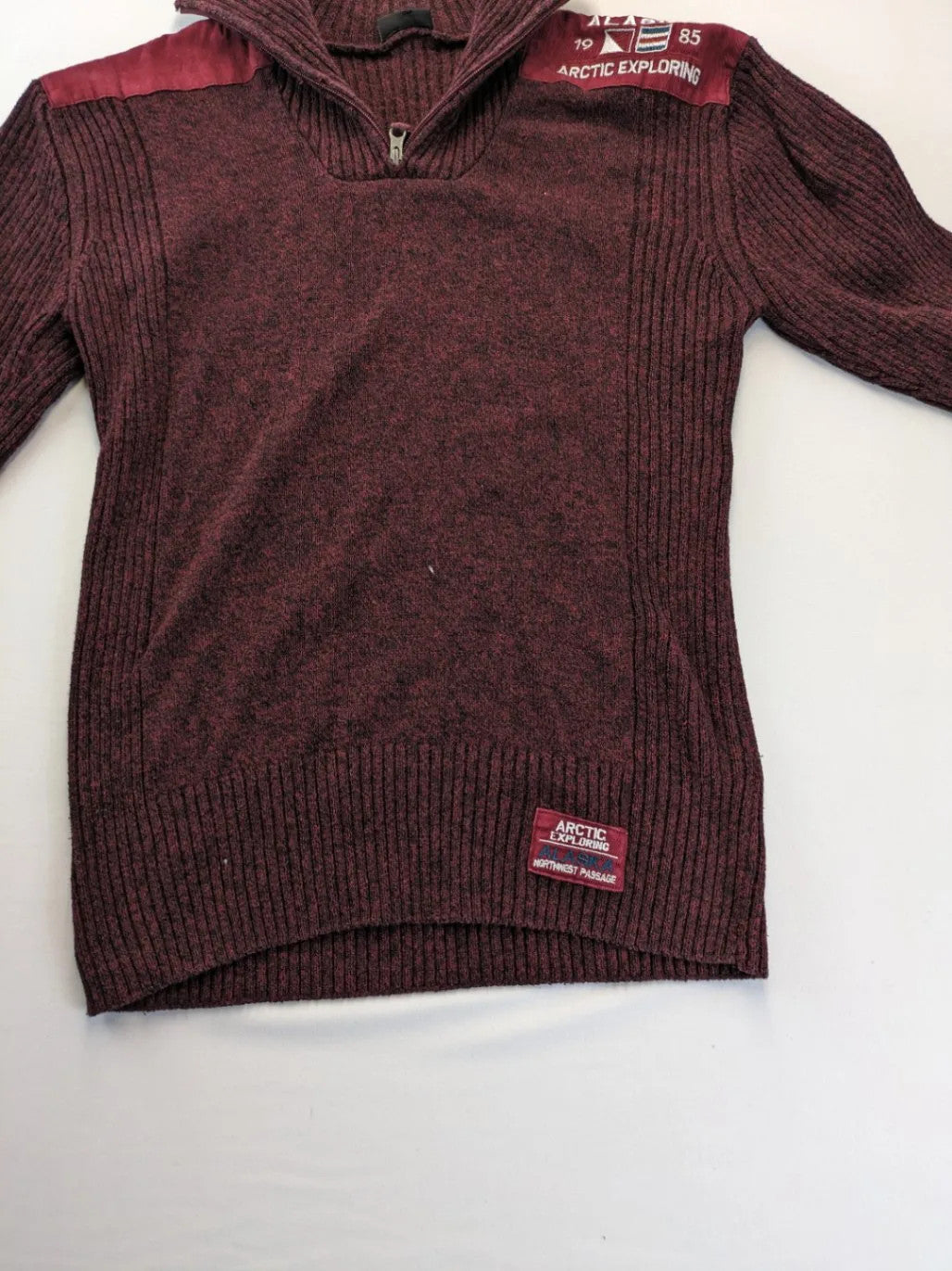 Infinity burgundy turtle neck jumper with quarter-zip and ribbed knit texture.