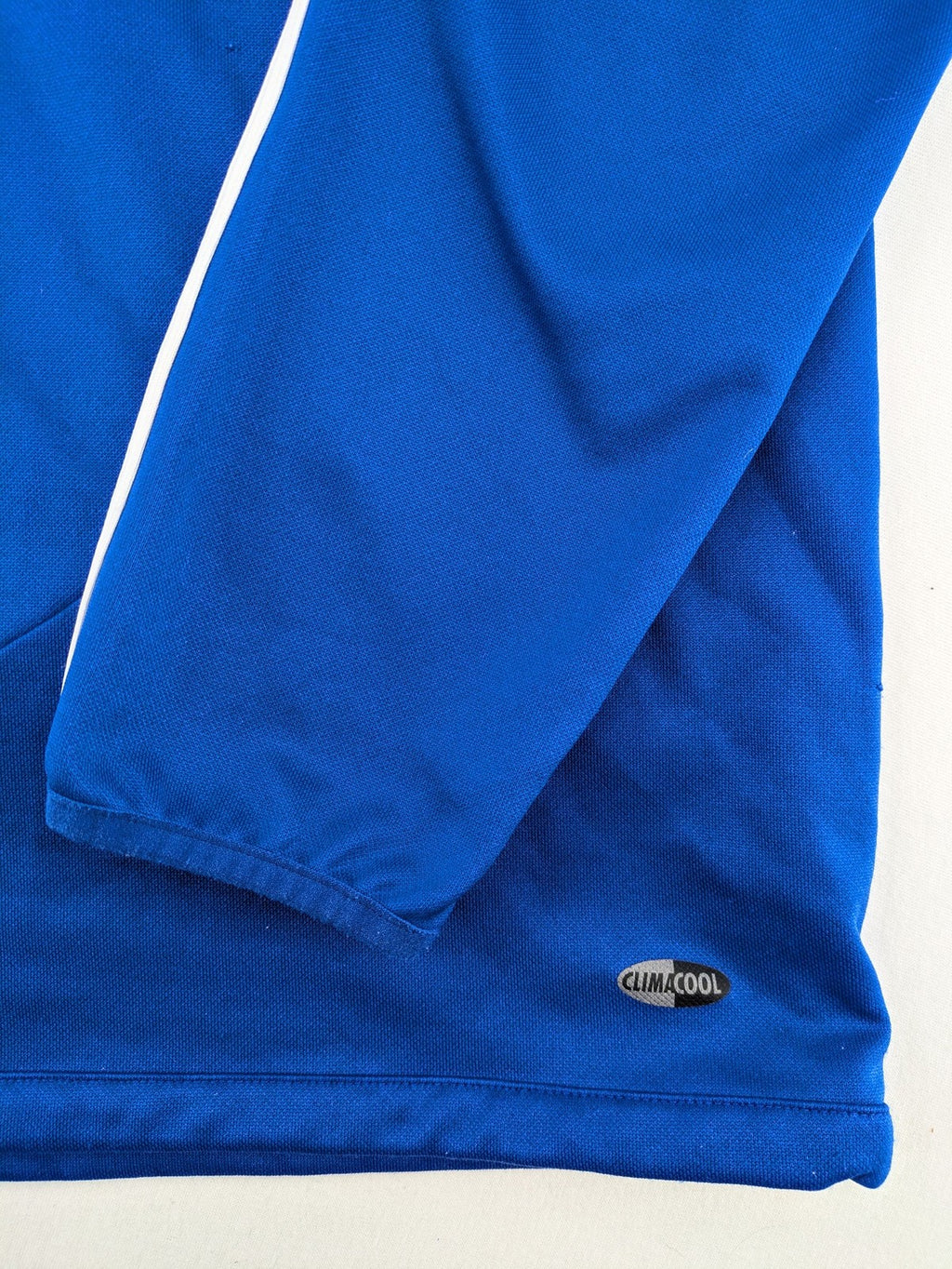 Adidas blue long sleeve top with white three stripes and 1/4 zip collar.