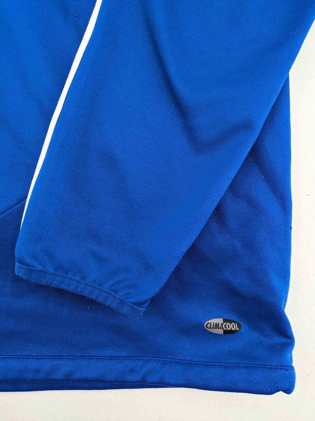 Adidas blue long sleeve top with white three stripes and 1/4 zip collar.