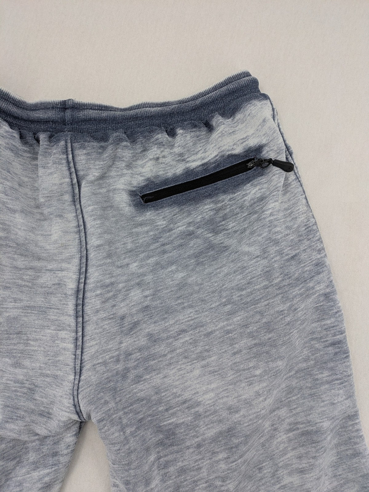 Nike grey acid wash jogger shorts with embossed logo and zip pockets.