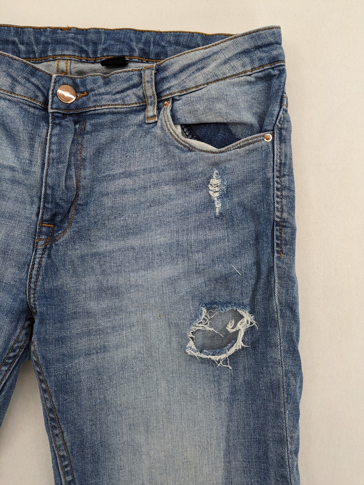 Denim blue distressed jeans shorts with frayed edges and a trendy used look.