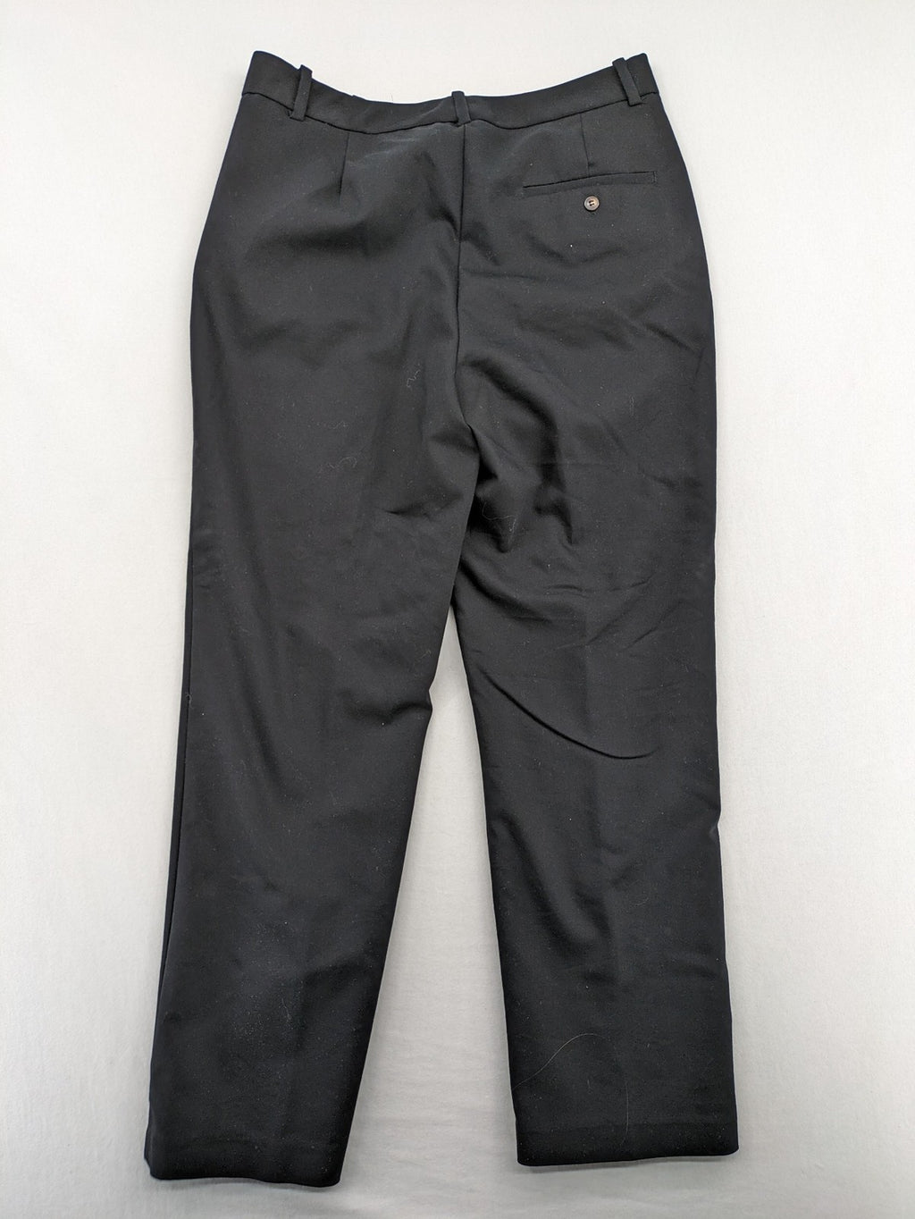 Zara black pants with front creases, subtle slit hem, and buttoned back pocket.