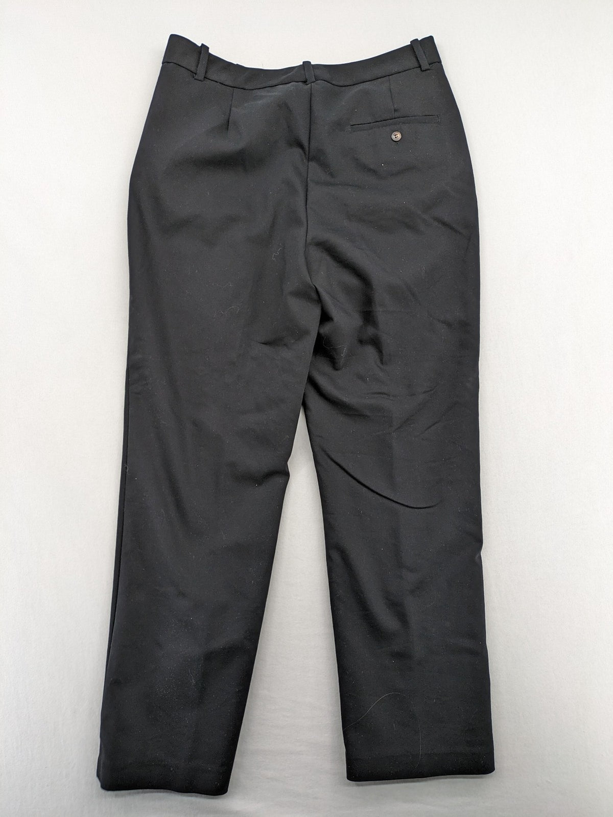 Zara black pants with front creases, subtle slit hem, and buttoned back pocket.
