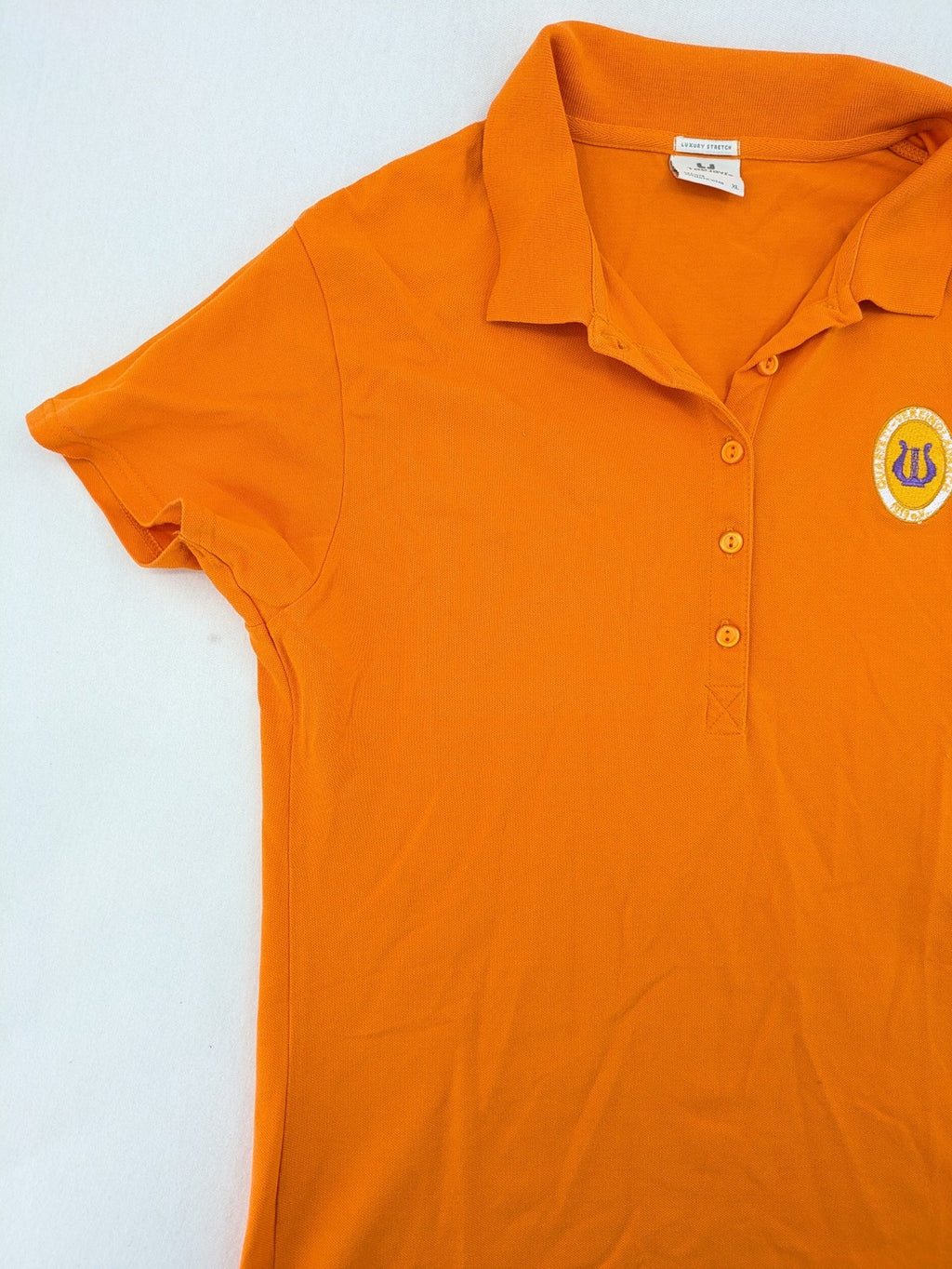 Teejays orange polo shirt with embroidered logo, classic collar, and button placket.