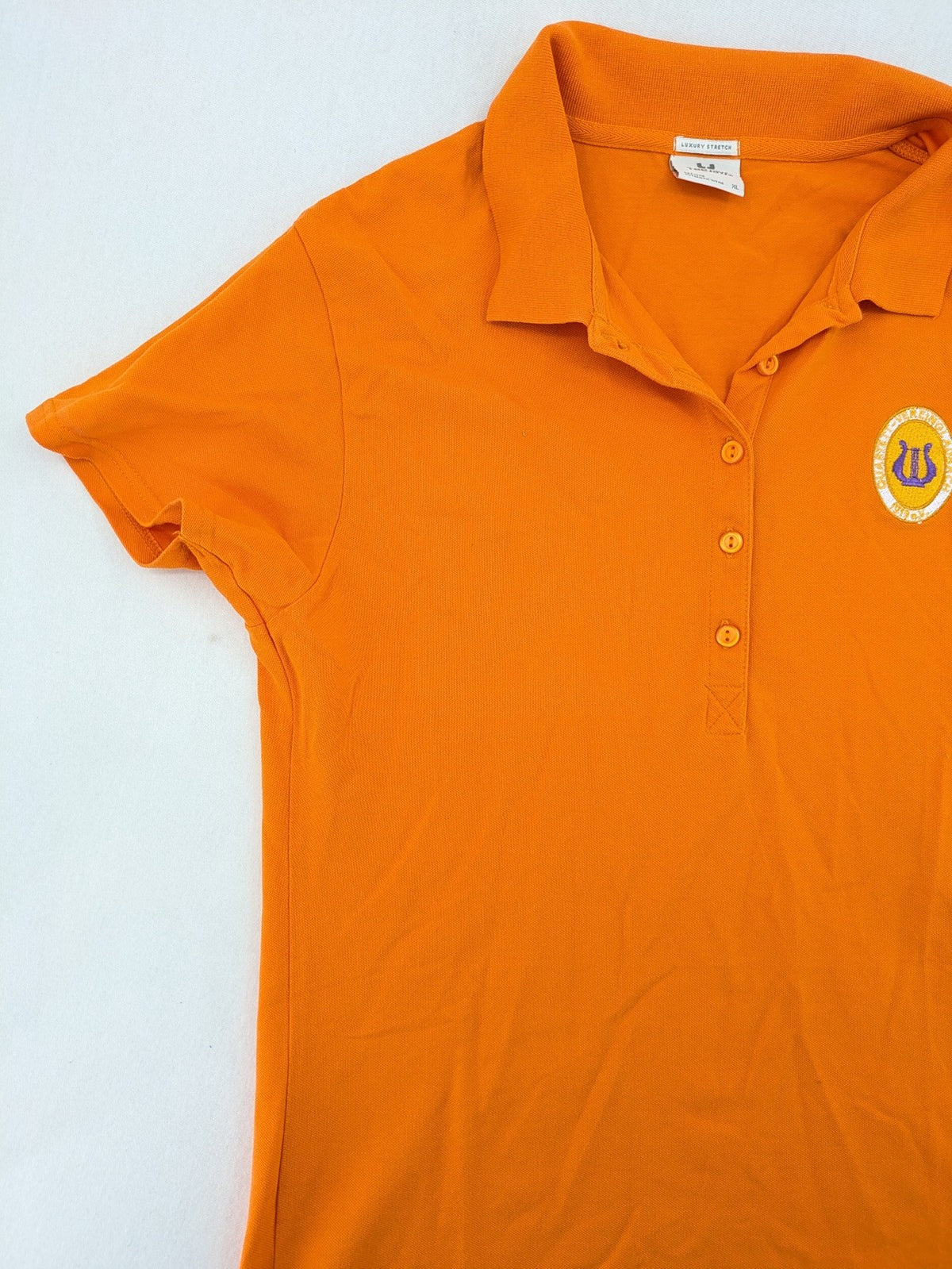 Teejays orange polo shirt with embroidered logo, classic collar, and button placket.
