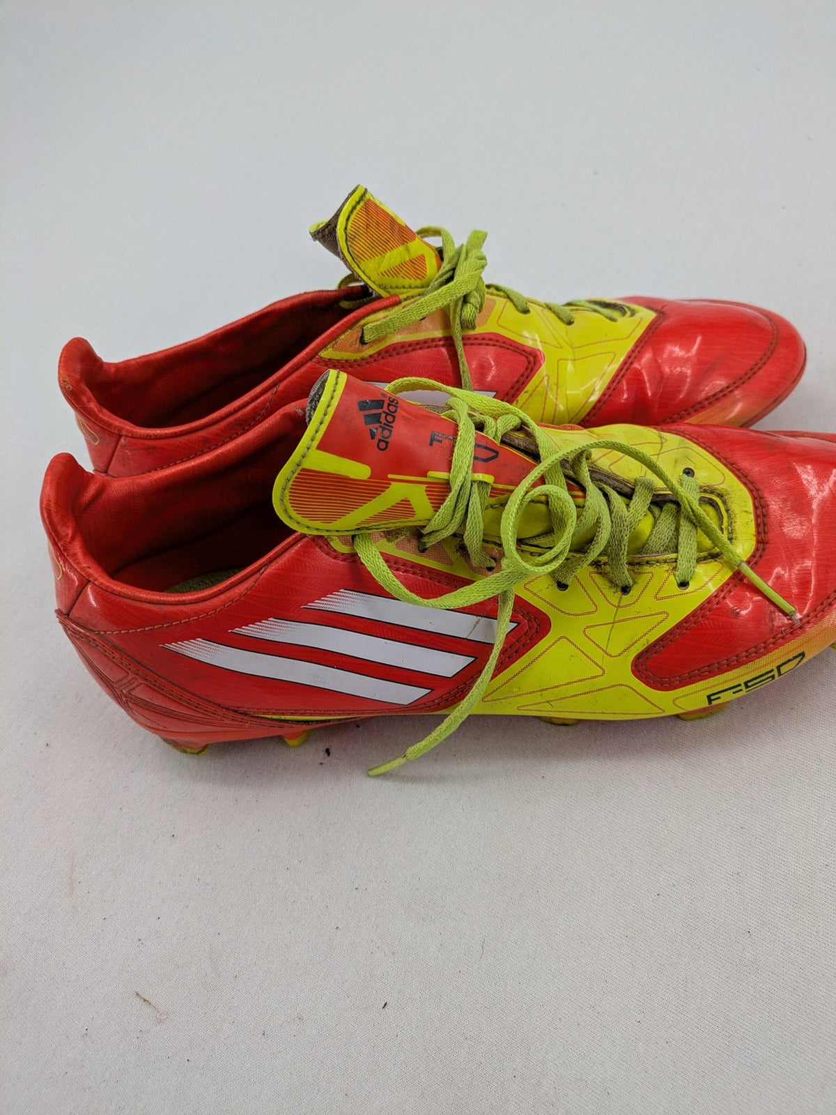 Adidas F50 soccer shoes red and yellow with three-stripe logo and lightweight synthetic material.