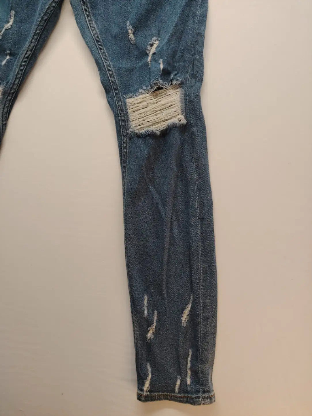 Damen blue skinny jeans with ripped details, five-pocket style, and classic button closure.