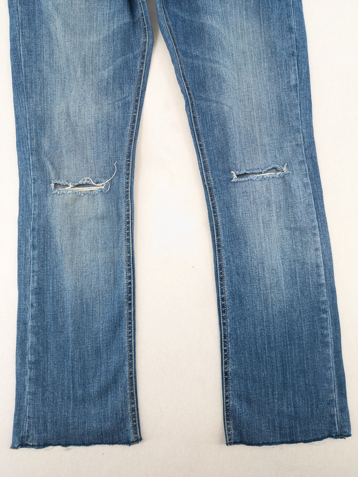 Tally Weijl blue bootcut jeans with distressed knees and raw hem detail.