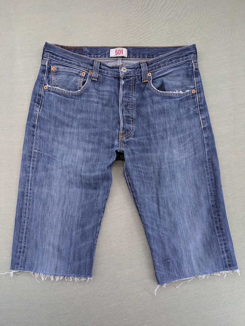 Levi's blue cut-off shorts with frayed hem, classic 5-pocket design, button fly.