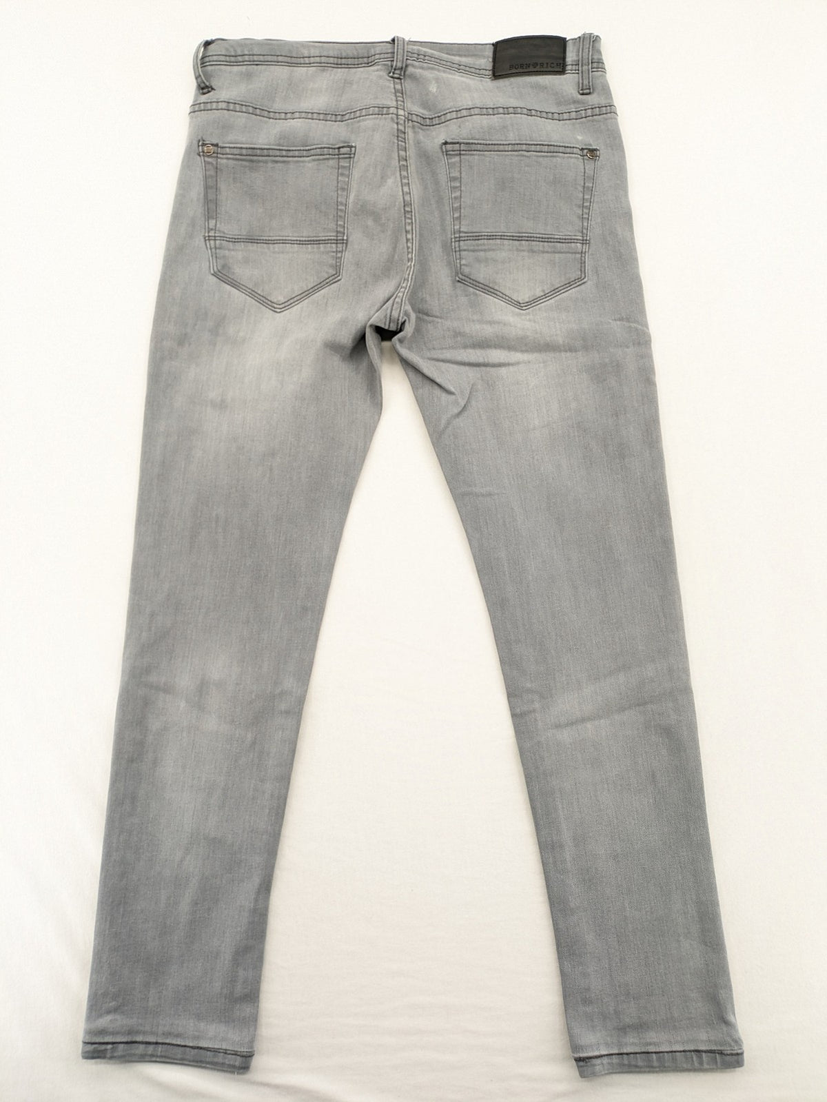 Born Rich grey slim fit jeans with logo patch and washed denim texture.