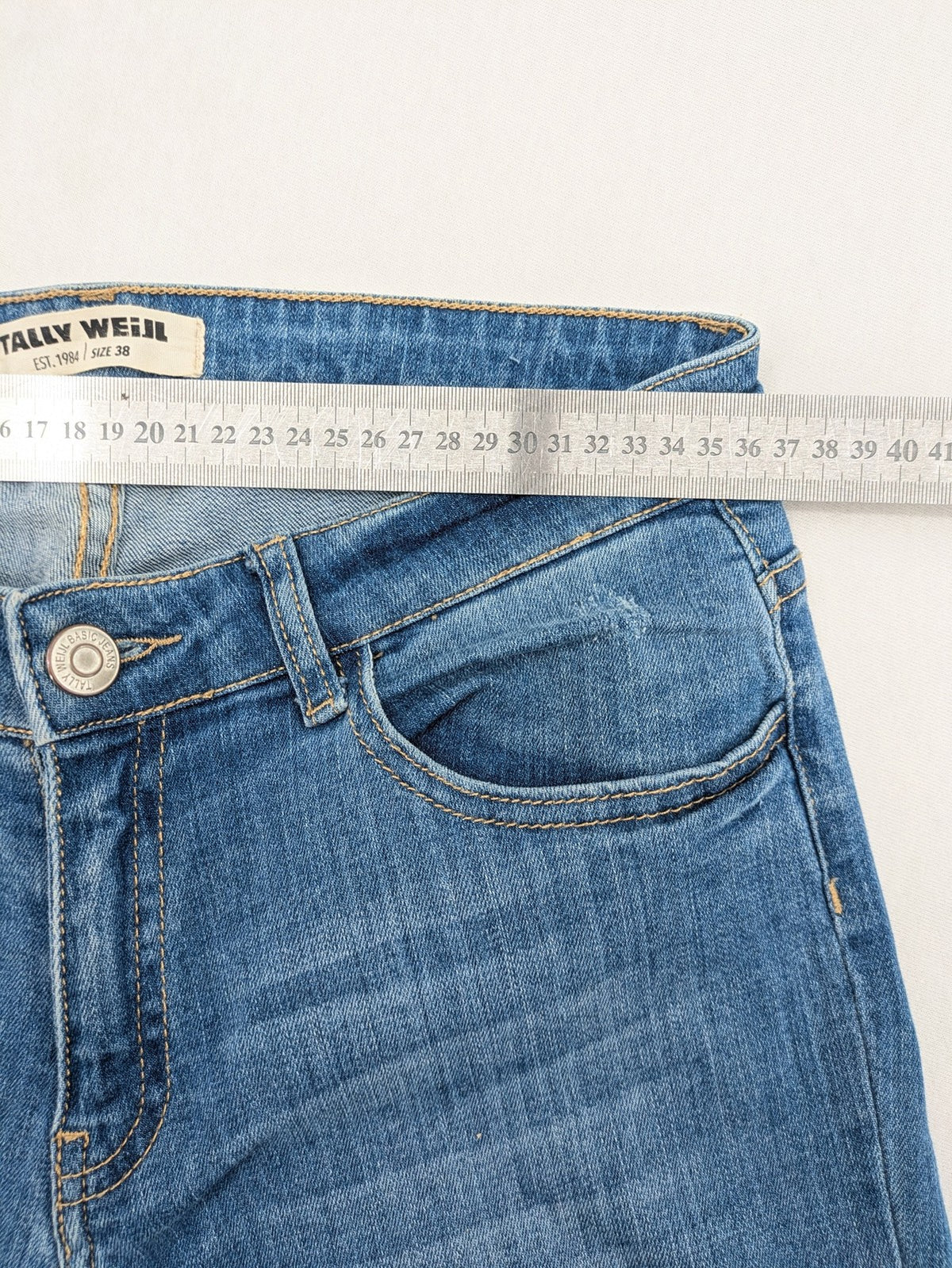Tally Weijl blue bootcut jeans with distressed knees and raw hem detail.