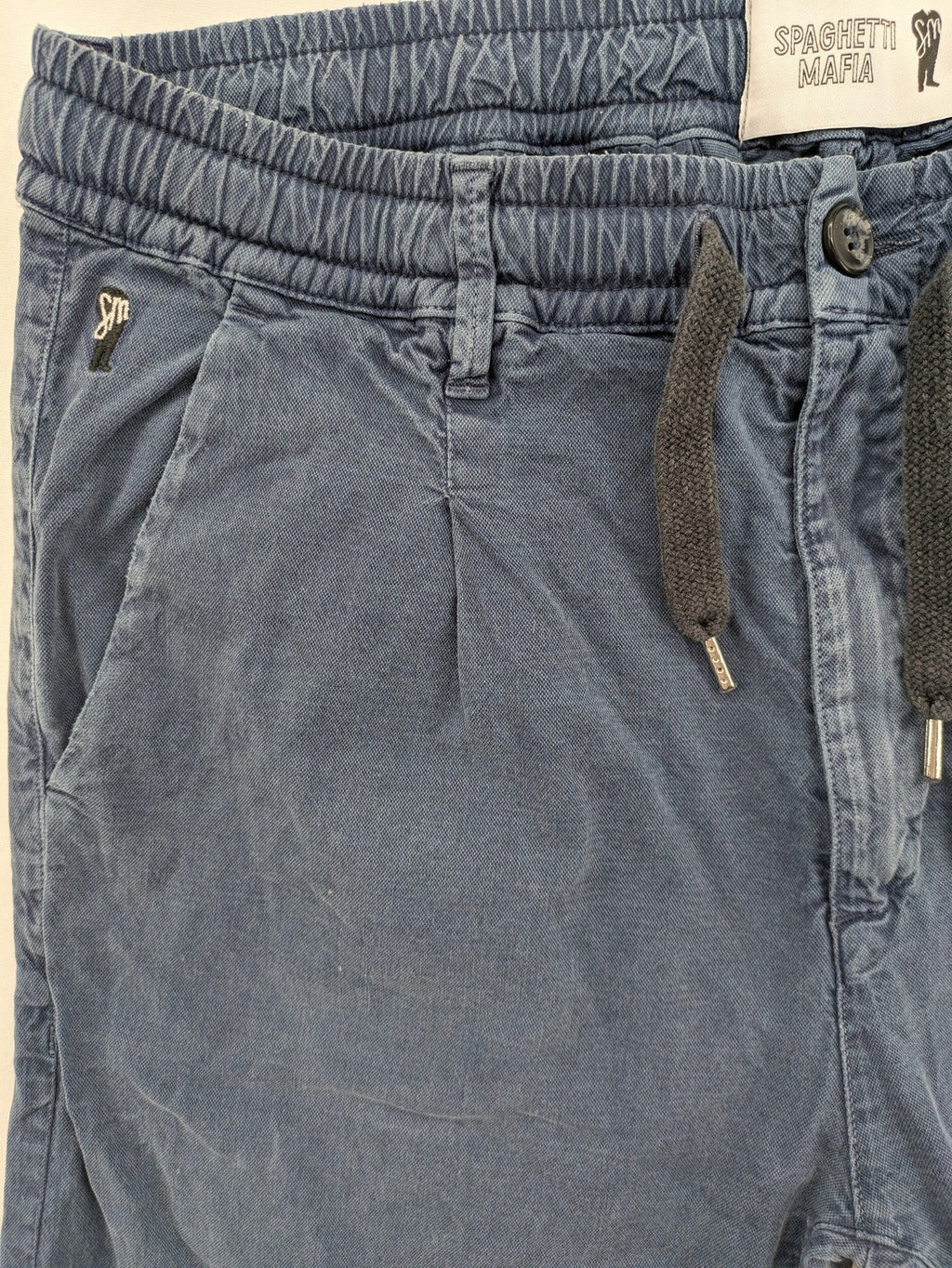 Spaghetti Mafia cream pants with elastic waistband, drawstring, and subtle front pleats.