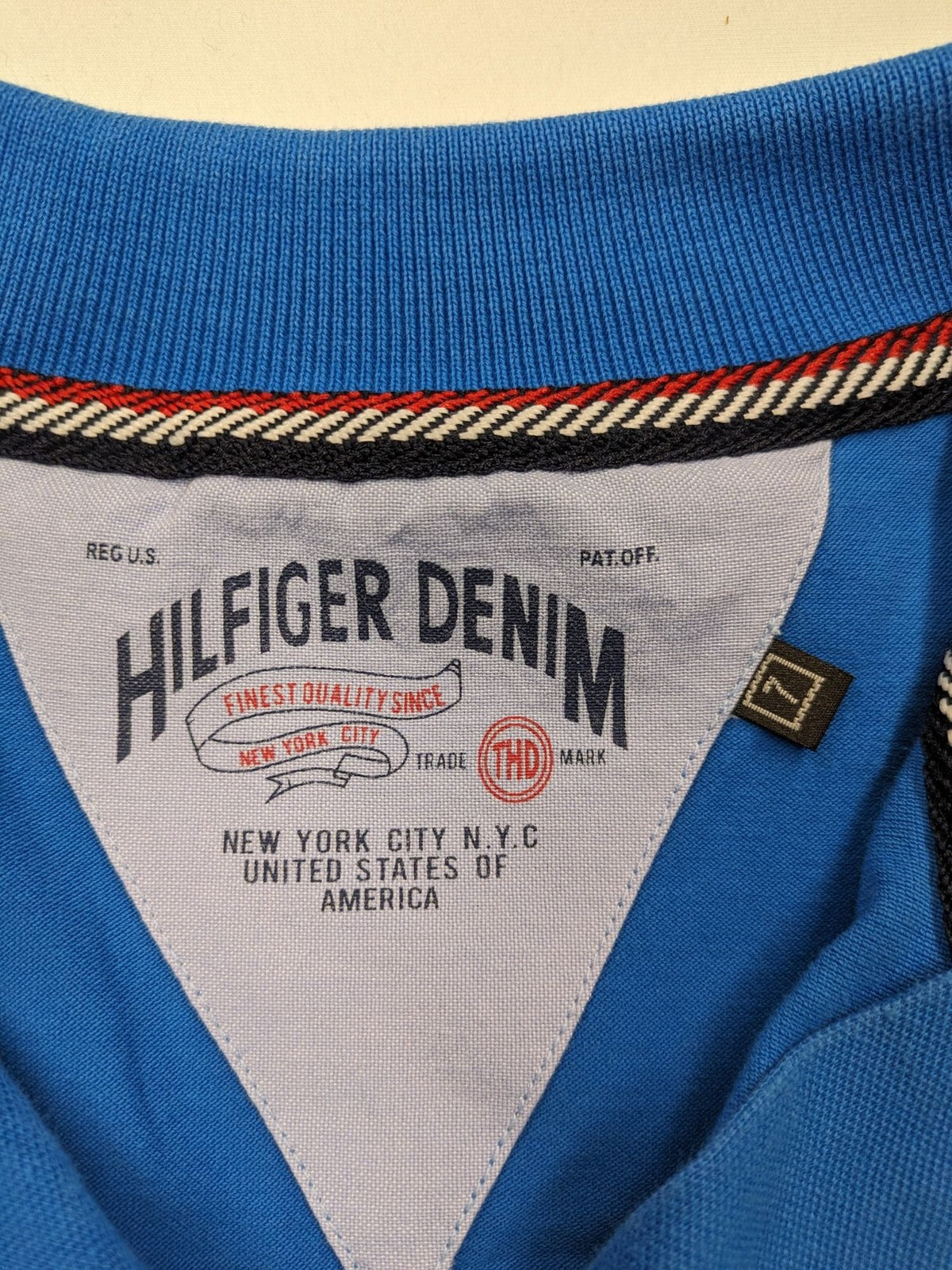 Tommy Hilfiger blue polo shirt with white stripes and embroidered logo on chest.