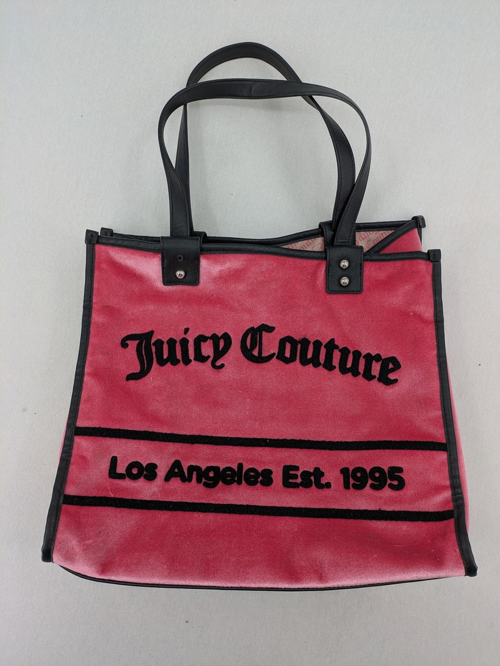 Juicy Couture pink velour handbag with oversized black logo and faux leather straps.