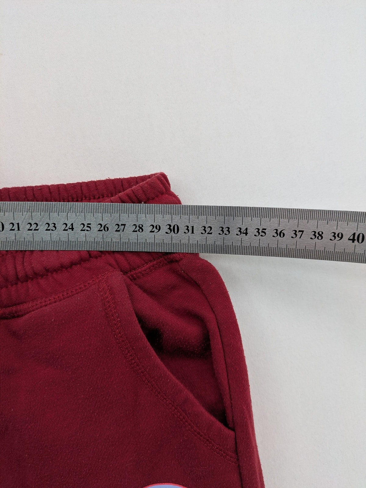 Harry Potter burgundy sweatpants featuring "HOGWARTS" print and Chibi graphic of Harry, Ron, Hermione.