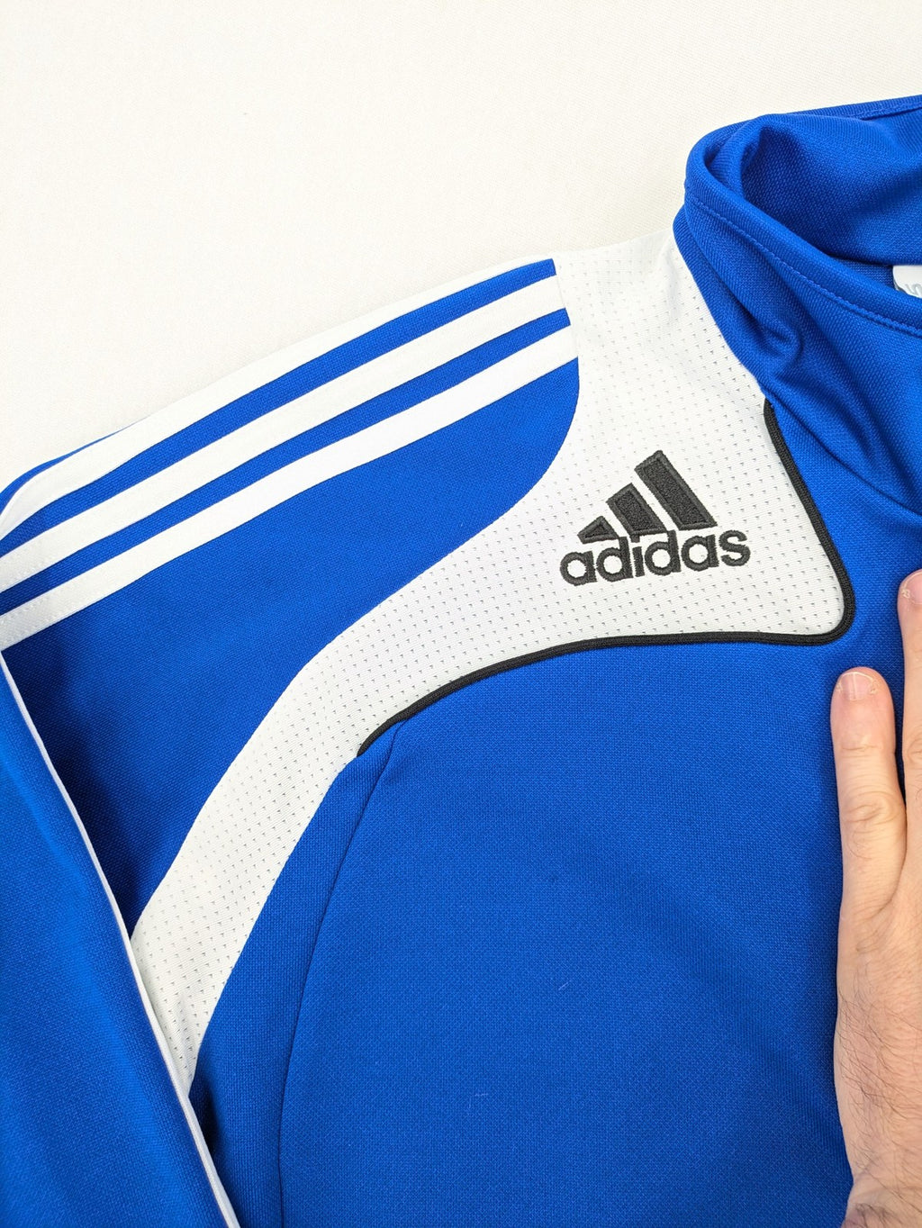 Adidas blue long sleeve top with white three stripes and 1/4 zip collar.