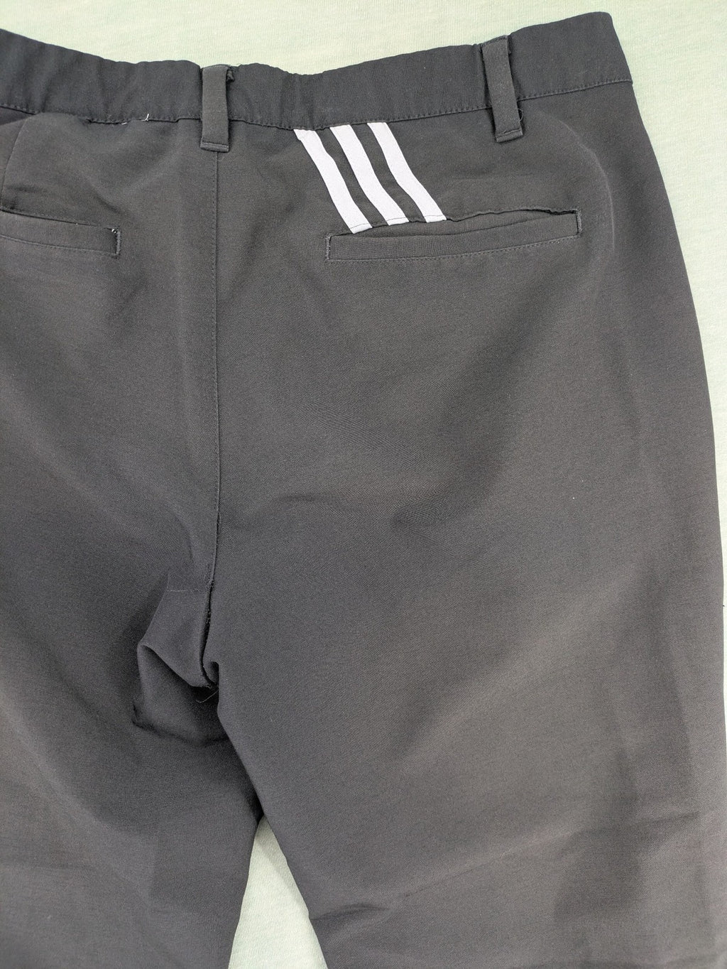 Adidas grey pants with 3-stripe logo, flat-front design, made from performance material.