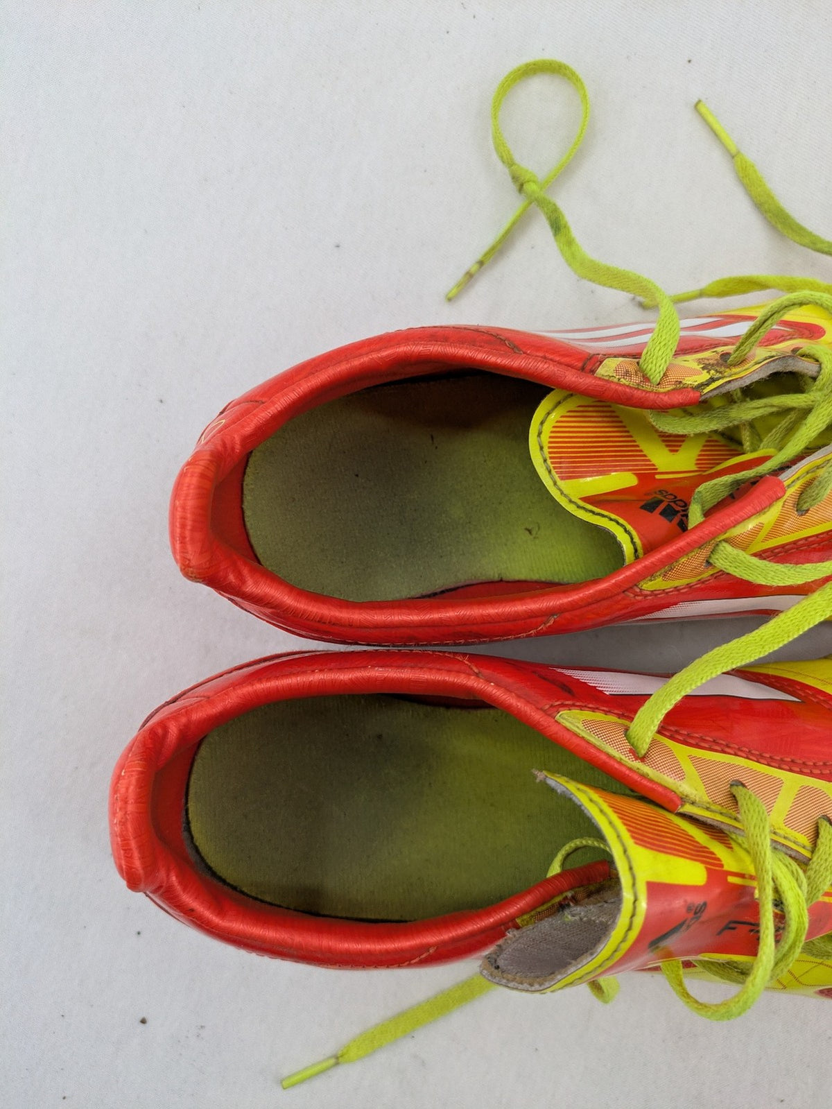 Adidas F50 soccer shoes red and yellow with three-stripe logo and lightweight synthetic material.