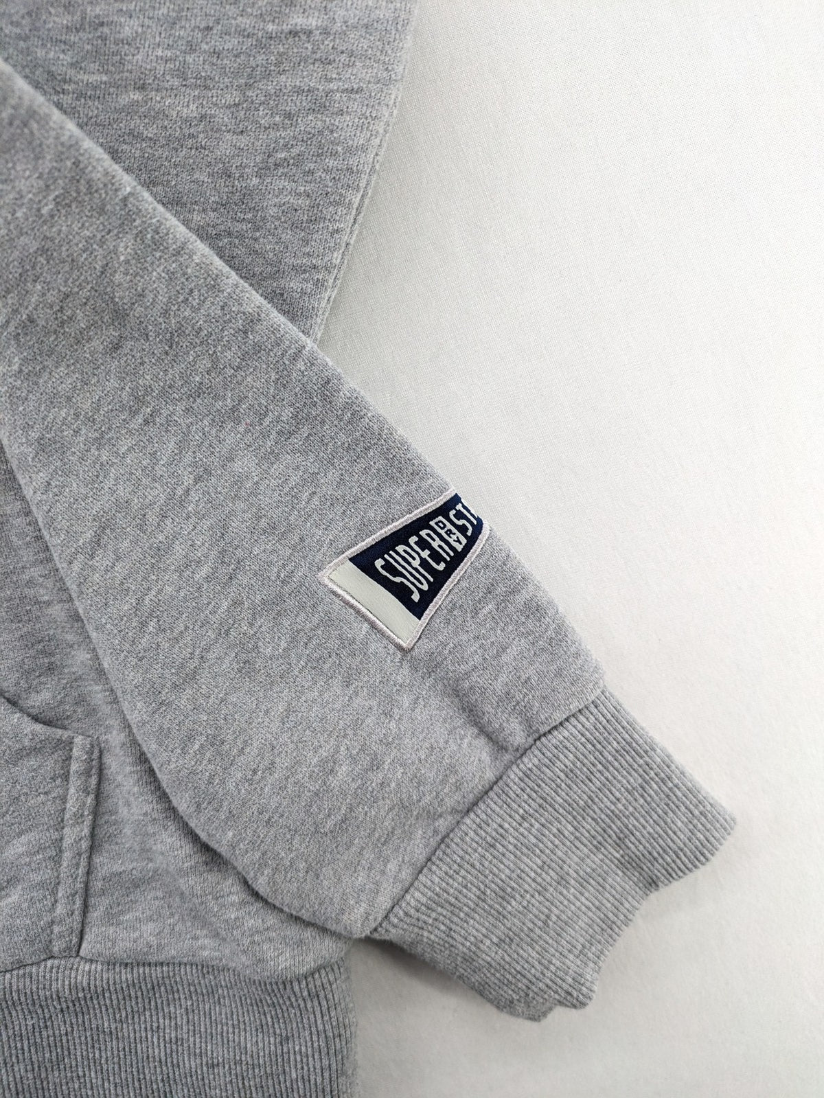 Superdry grey hoodie with Sonics logo, number 7 detail, kangaroo pocket, and drawstring hood.