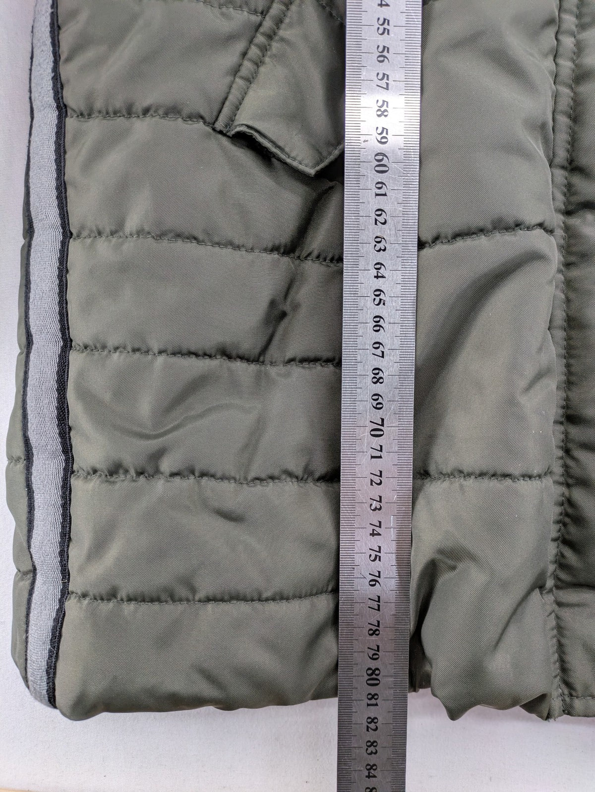 Vero Moda green puffer coat with quilted design and hood, featuring zipper and button closure.