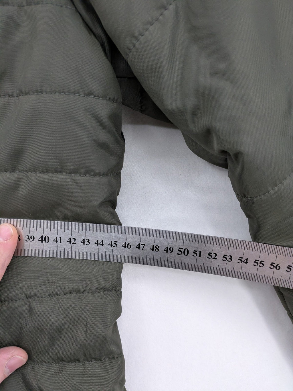 Vero Moda green puffer coat with quilted design and hood, featuring zipper and button closure.
