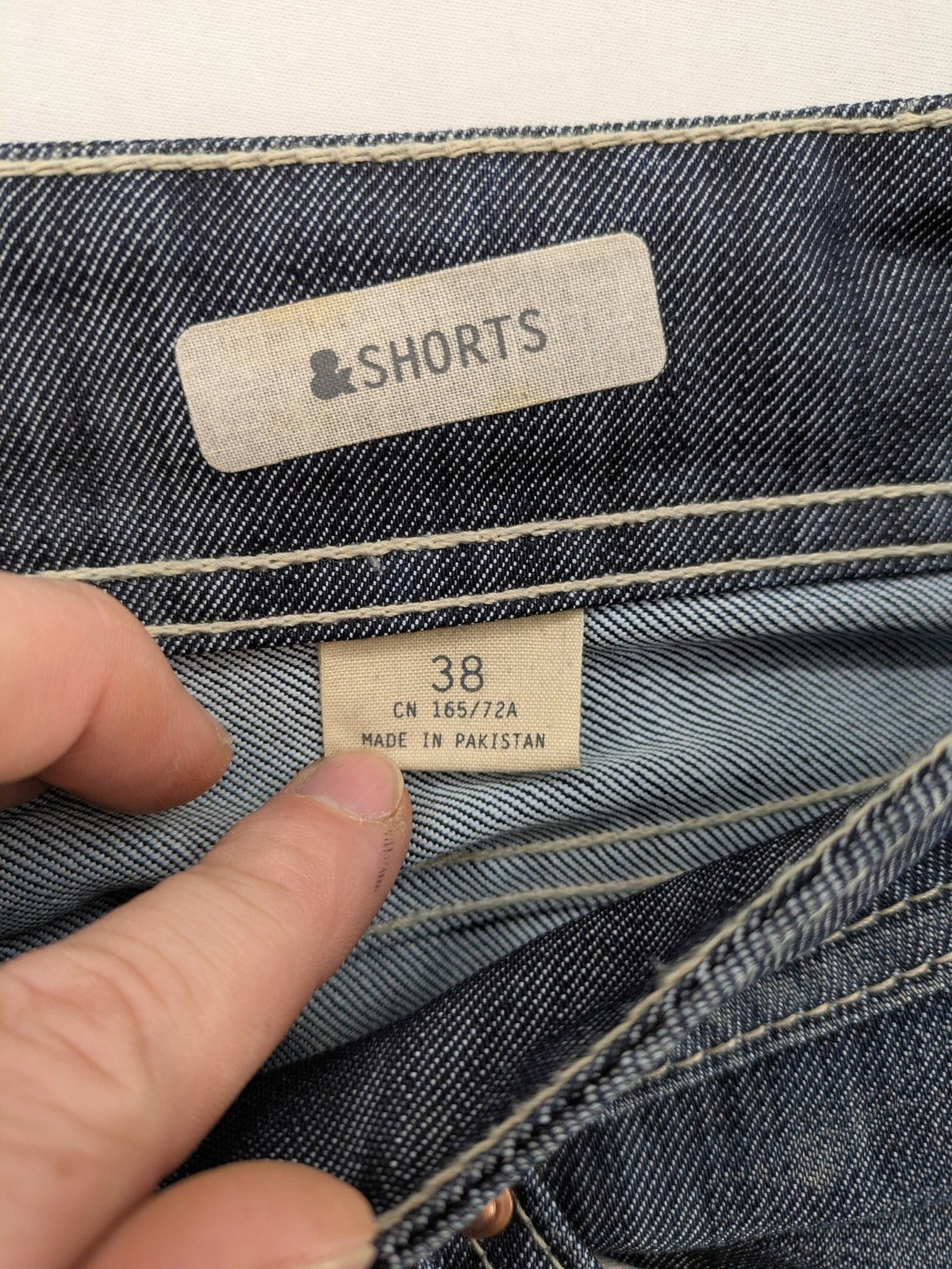 H&M blue denim shorts with rolled cuffs and back patch pockets, mid-rise fit.