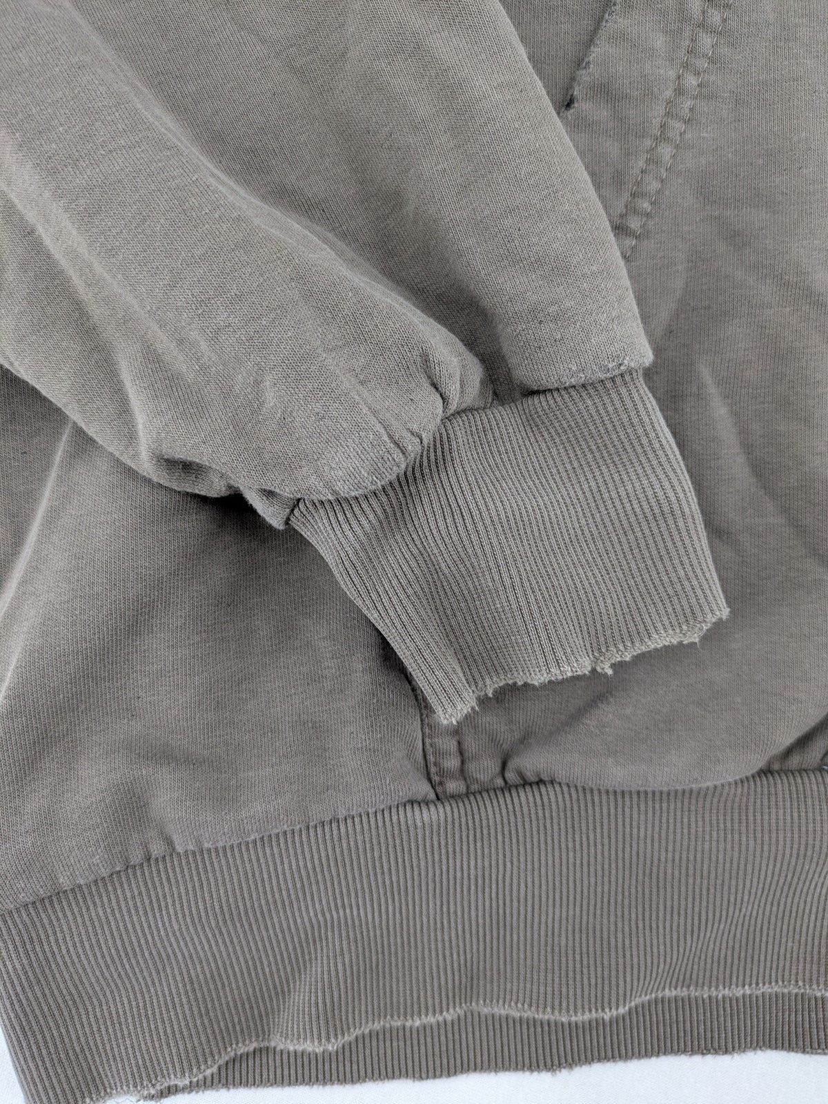 Mosquito grey hoodie with distressed cuffs and subtle logo on the chest.