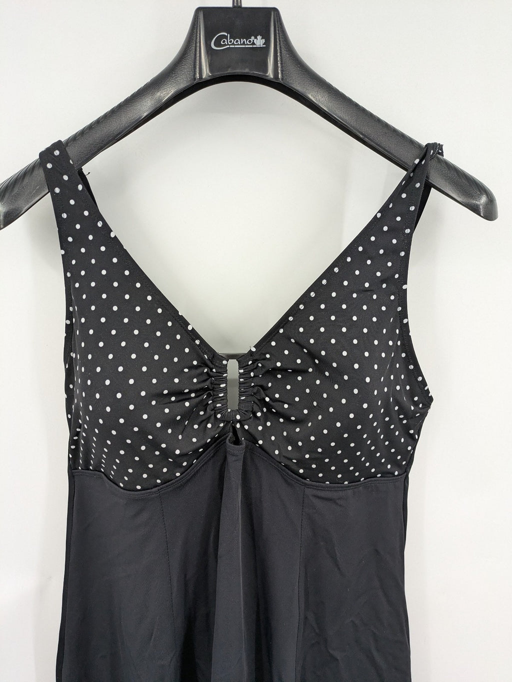 Elegante black swimsuit with white polka dots, V-neck, adjustable straps, and padded cups.
