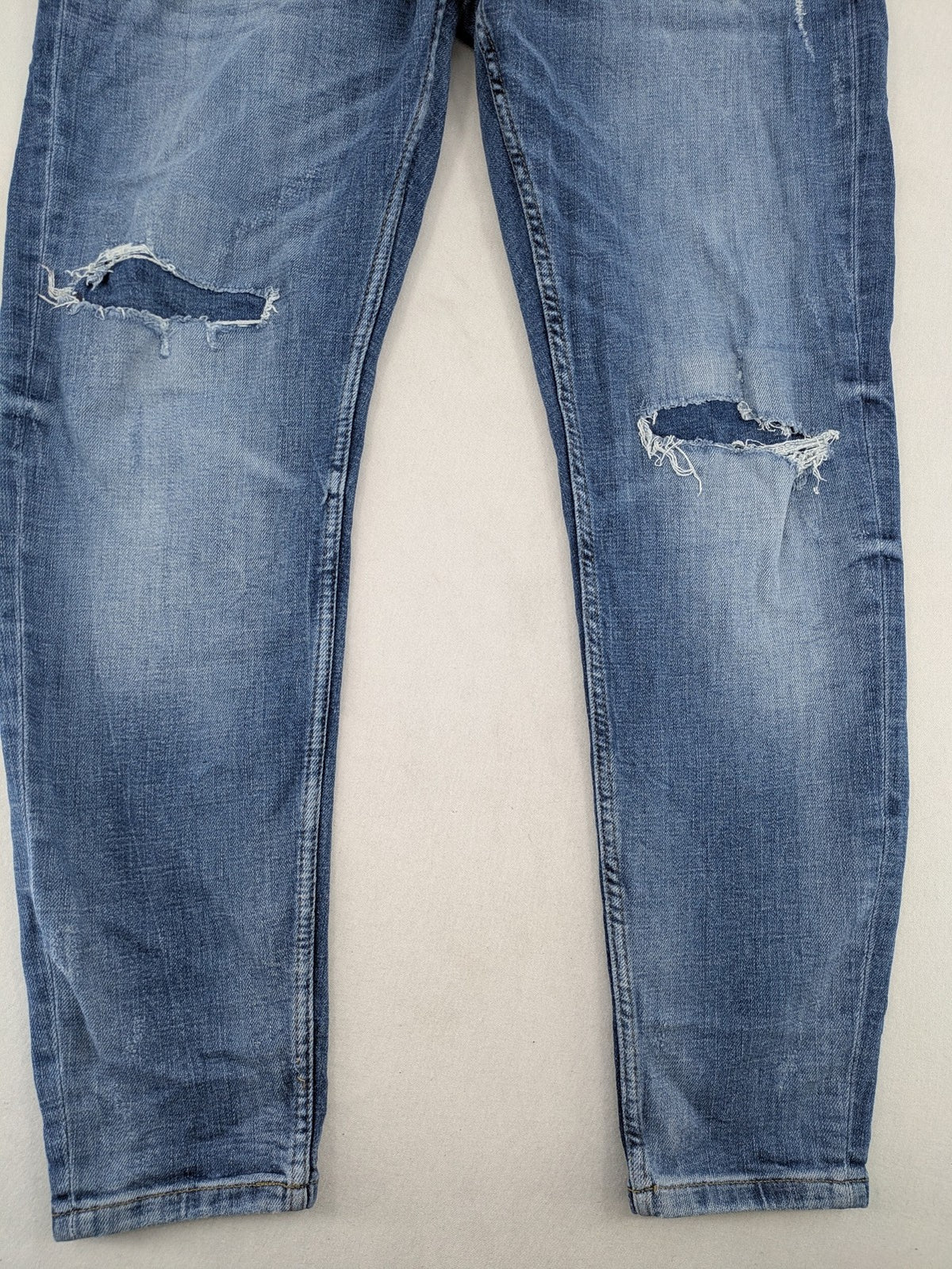 Zara blue straight jeans with distressed ripped knees and button-fly closure.