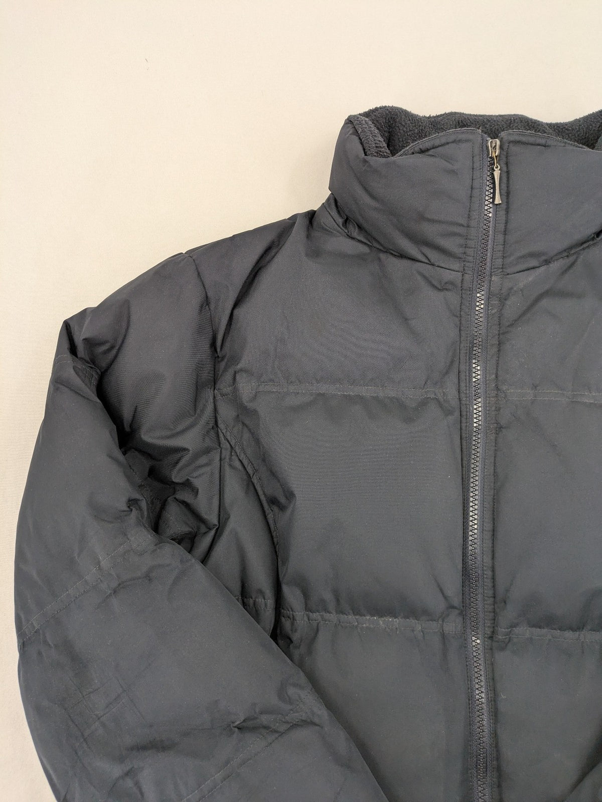 Identic black puffer jacket with quilted design and fleece-lined high collar.