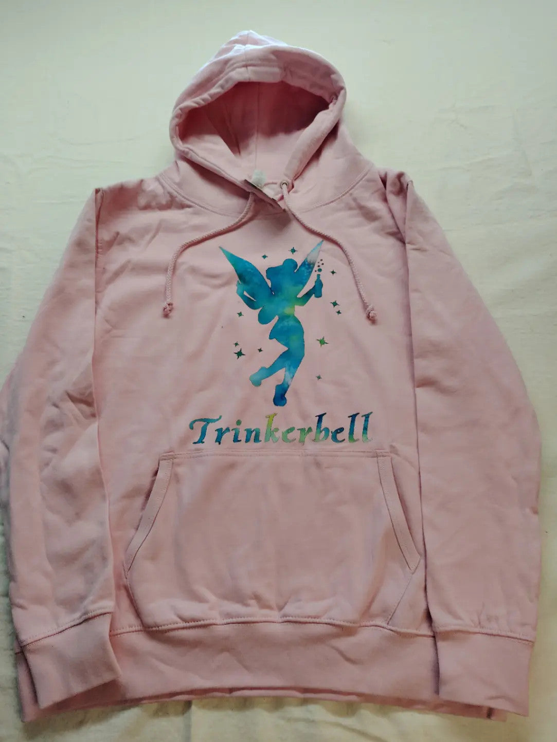 Just Hoods pink zip-through hoodie with "Trinkerbell" graphic, kangaroo pocket, drawstring hood.