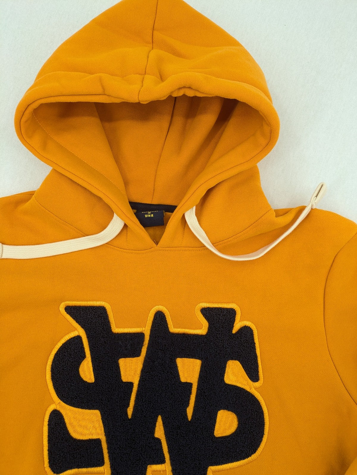 Superdry orange turtle neck jumper with textured logo patch and number 7 detail.