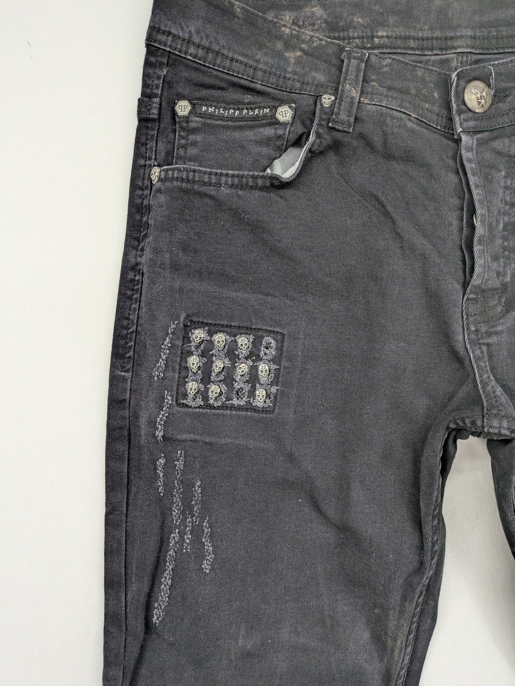 Philipp Plein black straight jeans with distressed finish and skull patch detail.