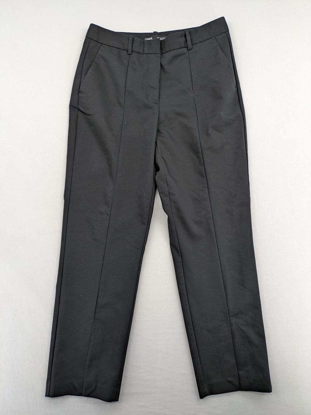 Zara black pants with front creases, subtle slit hem, and buttoned back pocket.
