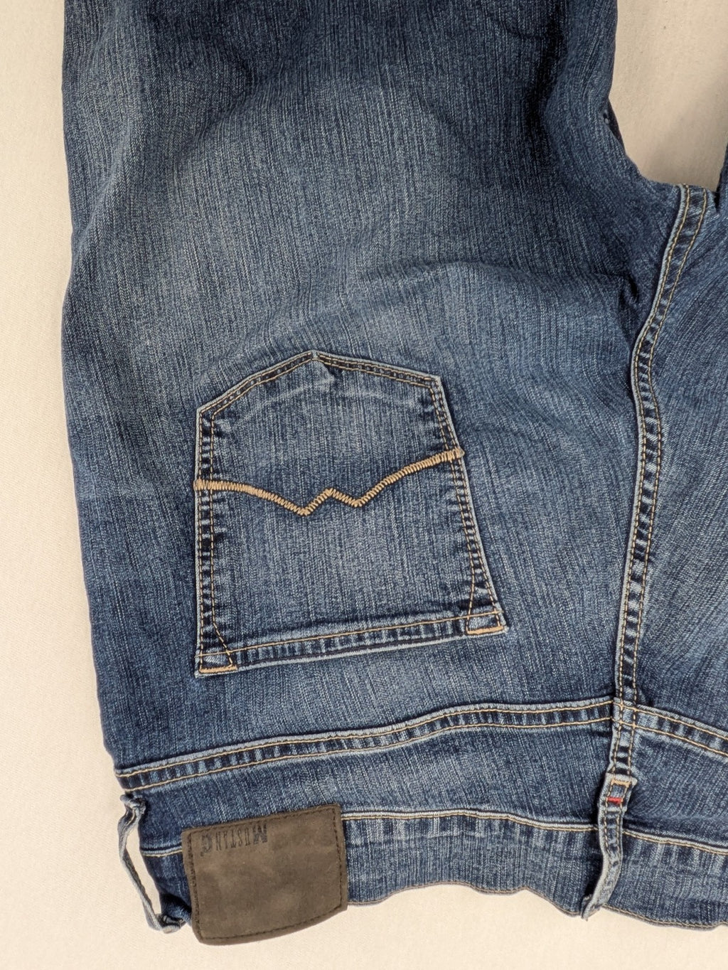 Mustang blue bootcut jeans with custom painted floral designs on both legs.