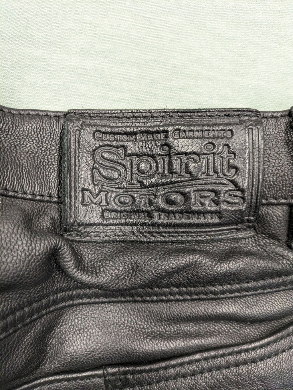 Spirit Motors black leather chaps with red and white accents, 5-pocket style, reinforced knees.