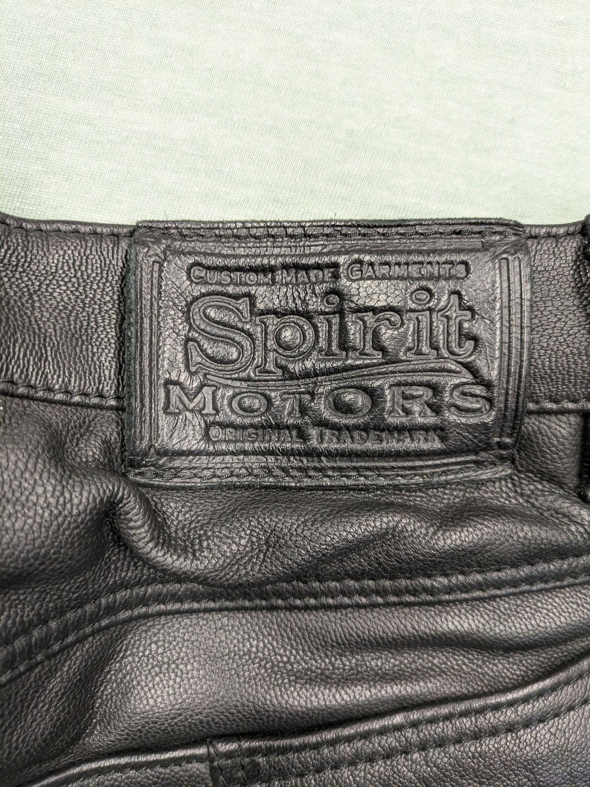 Spirit Motors black leather chaps with red and white accents, 5-pocket style, reinforced knees.