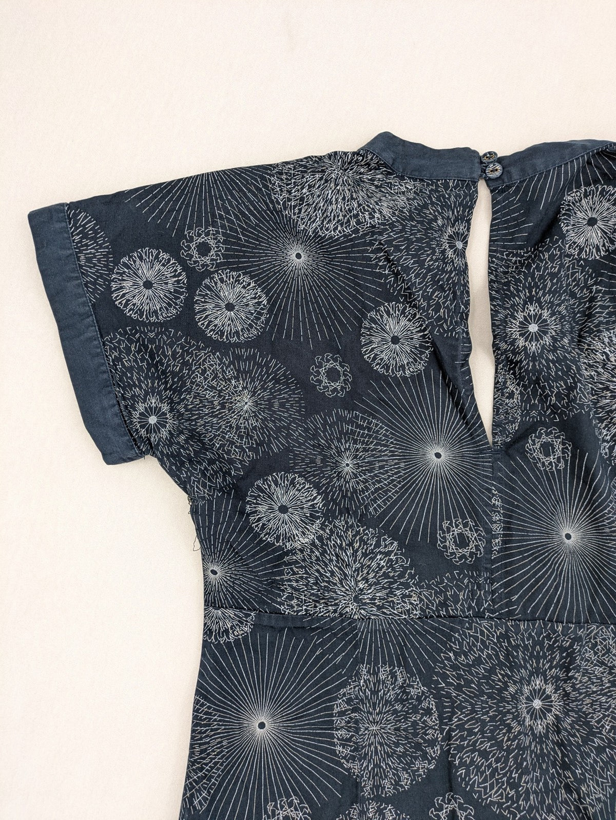 Muster navy dress with white abstract dandelion print, V-neck and collar details.