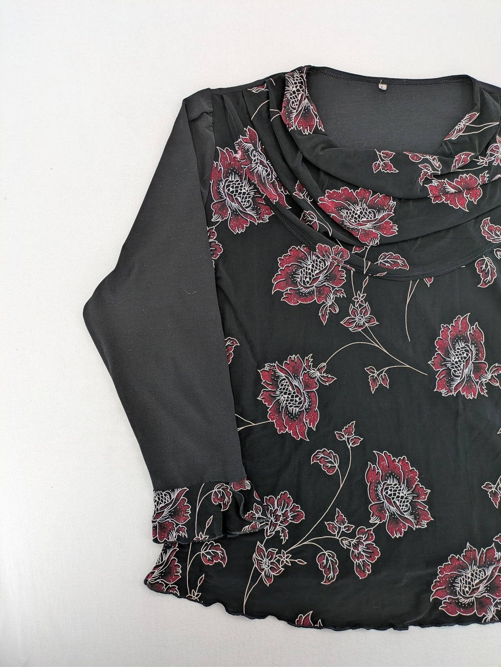 Damen black top with burgundy and white floral print, waterfall collar, and ruffled sleeves.