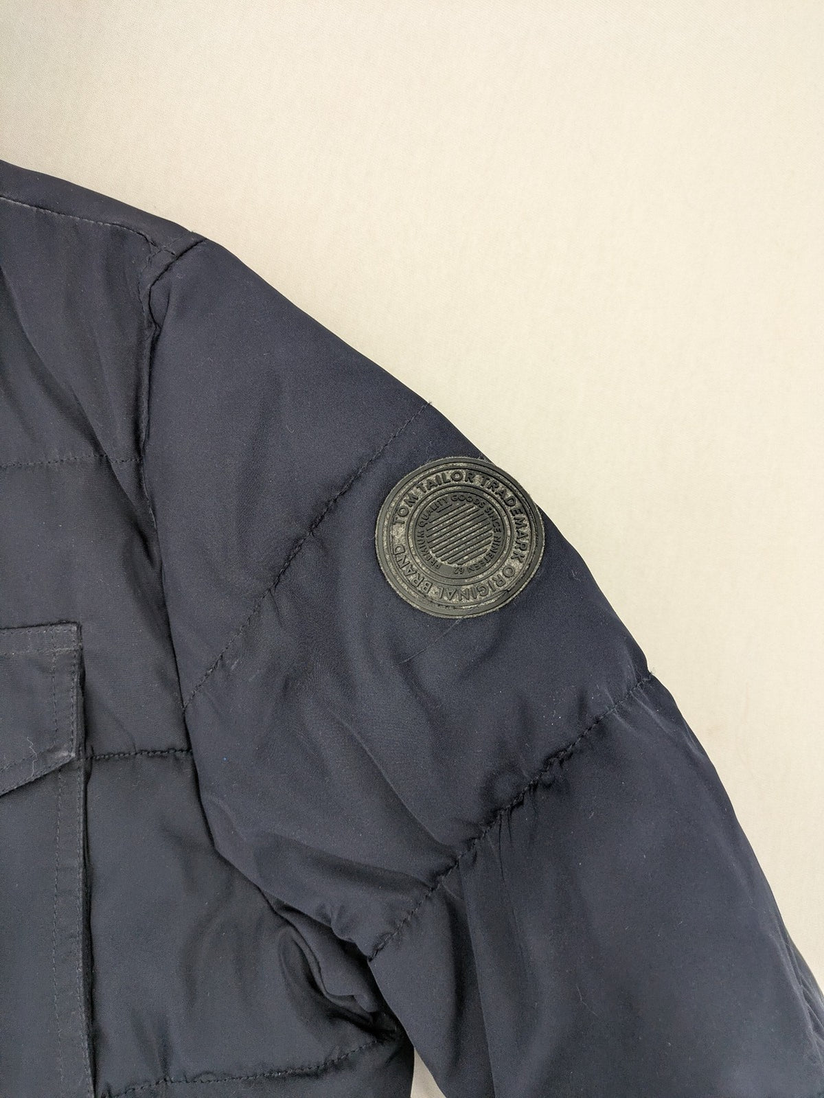 Tom Tailor navy puffer jacket with quilted design and adjustable hood, featuring multiple pockets.