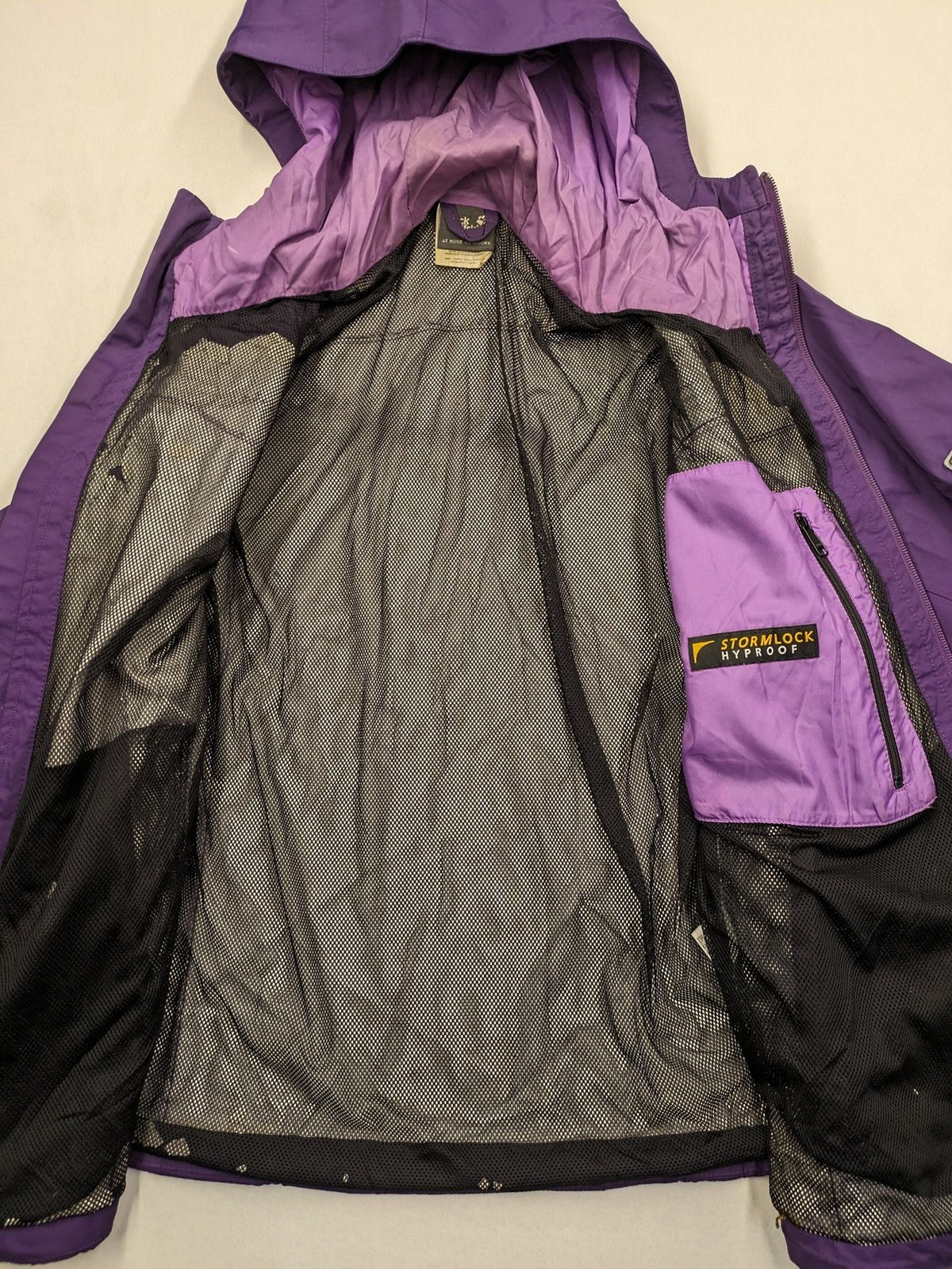 Jack Wolfskin purple outdoor jacket with adjustable hood and full zip, lightweight Stormlock material.