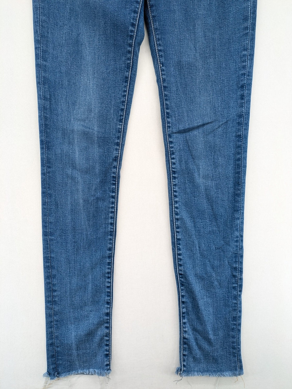 Levi's blue skinny jeans with raw hem, classic five-pocket design, and zip fly.