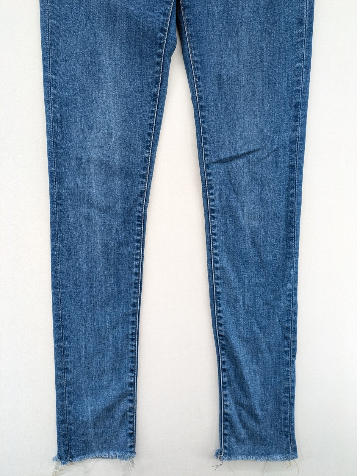 Levi's blue skinny jeans with raw hem, classic five-pocket design, and zip fly.