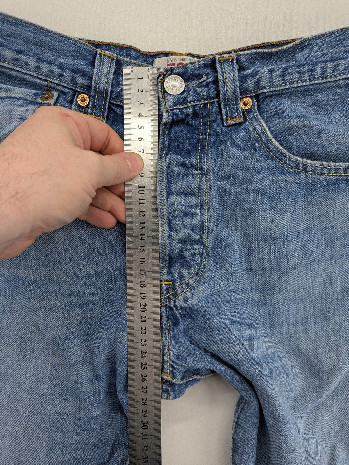 Levi's blue straight jeans with button-fly and distressed knee rips.