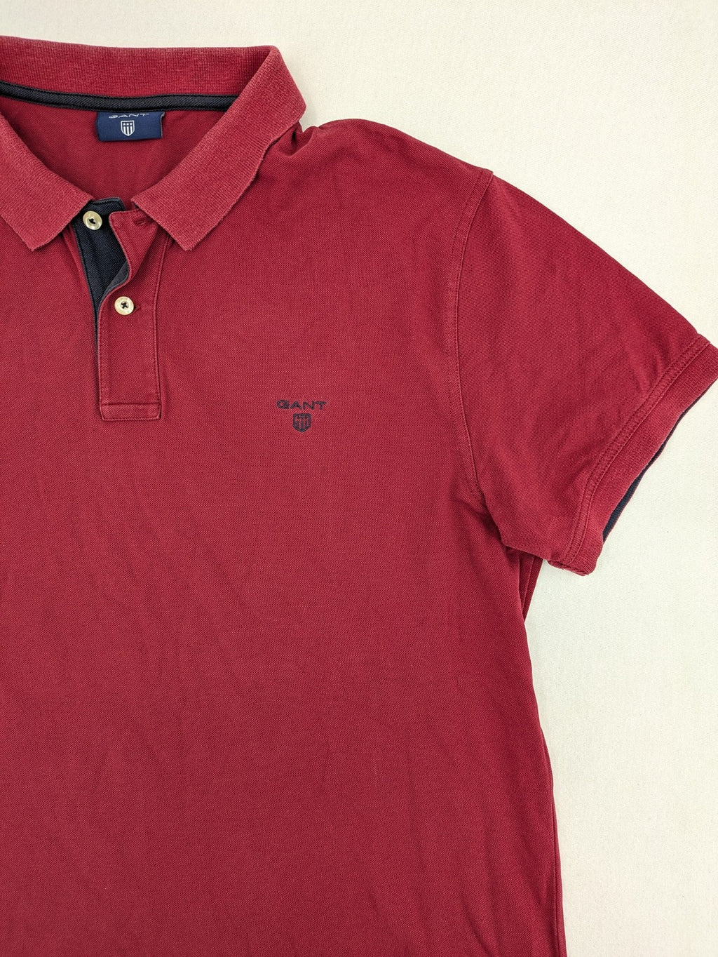 GANT burgundy polo shirt with embroidered shield logo and contrasting navy collar details.